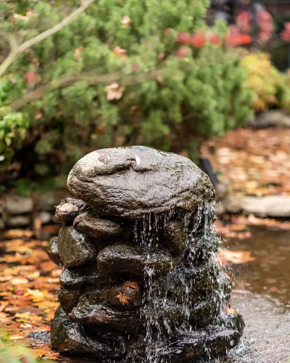 Water running over a stacked stone fountain in a garden pond