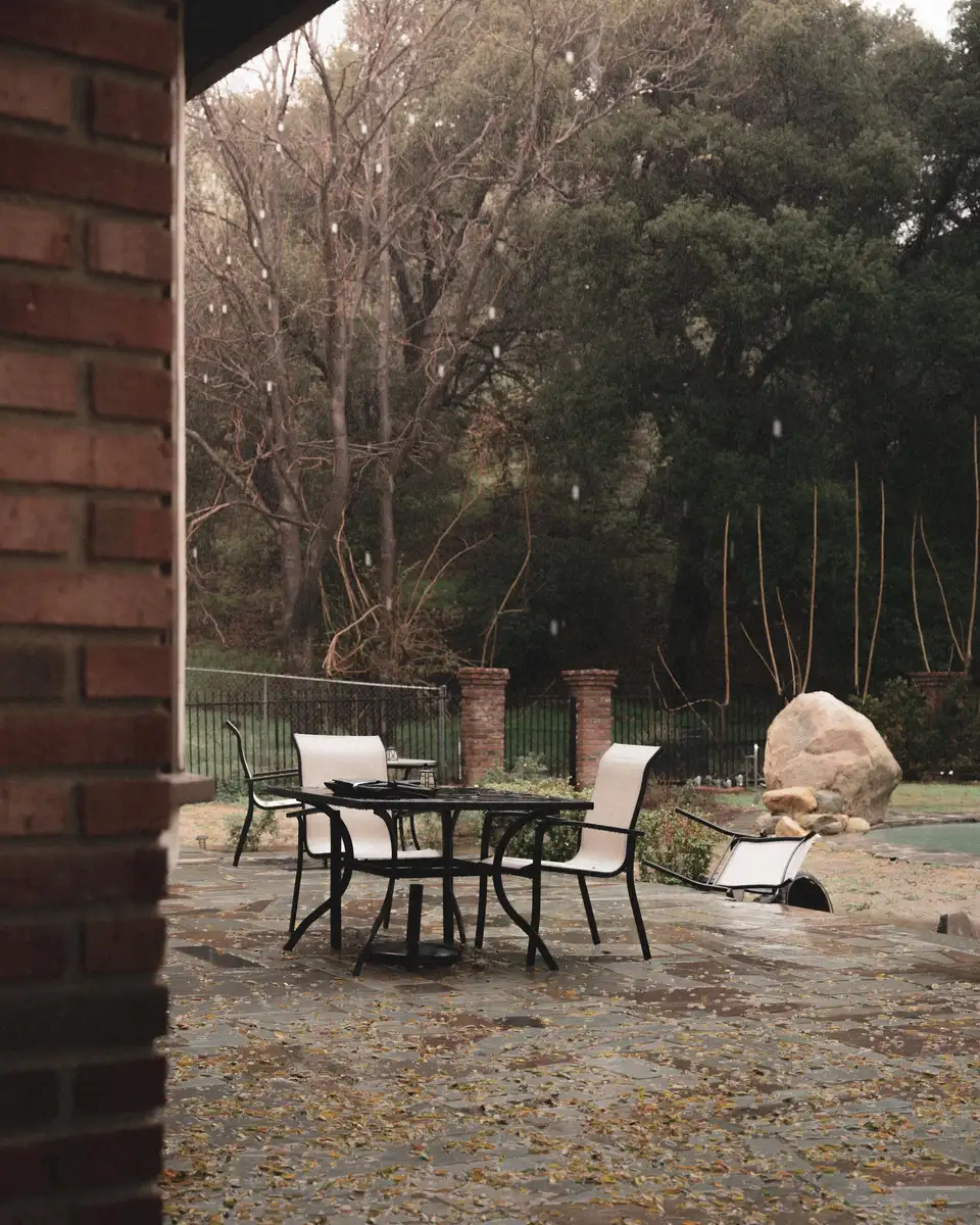 A table and chairs on a wet stone terrace in autumn